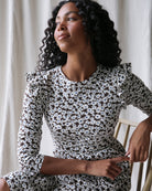 Woman wearing a black and white patterned dress sitting on a chair.