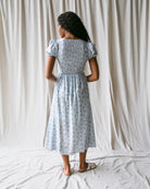 Woman wearing a light blue floral dress against a plain white background