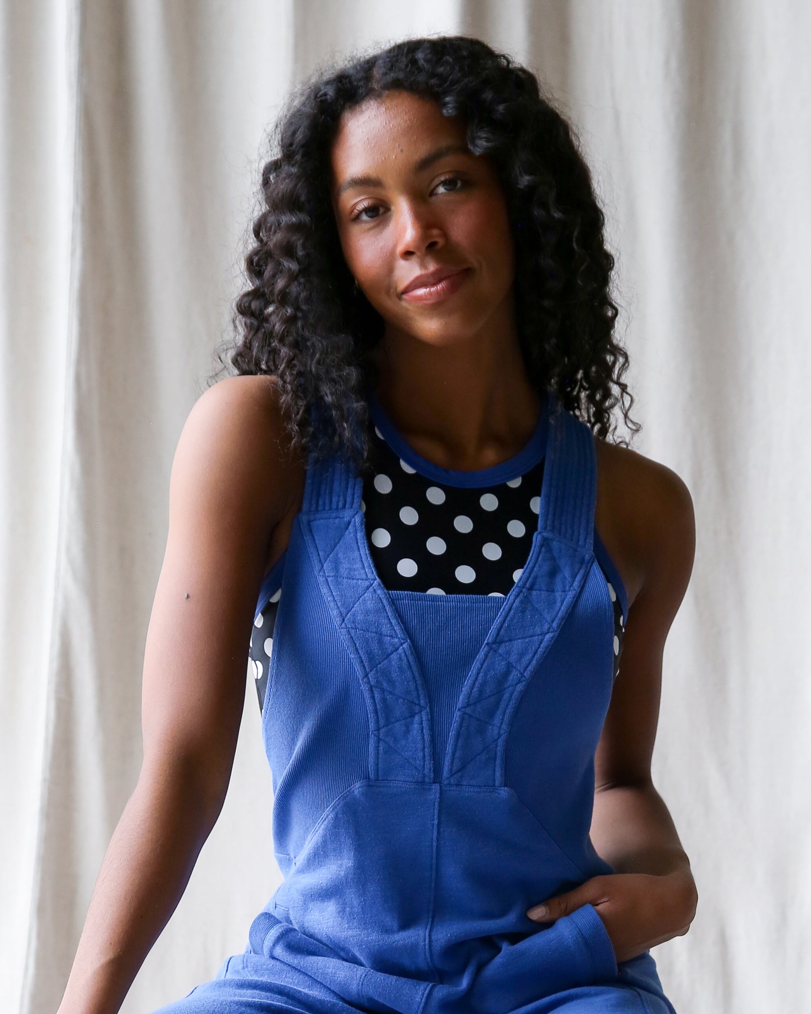Woman wearing a blue dress over a polka dot shirt against a neutral background