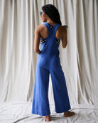 Person wearing a blue jumpsuit with white polka dots in front of a white curtain.