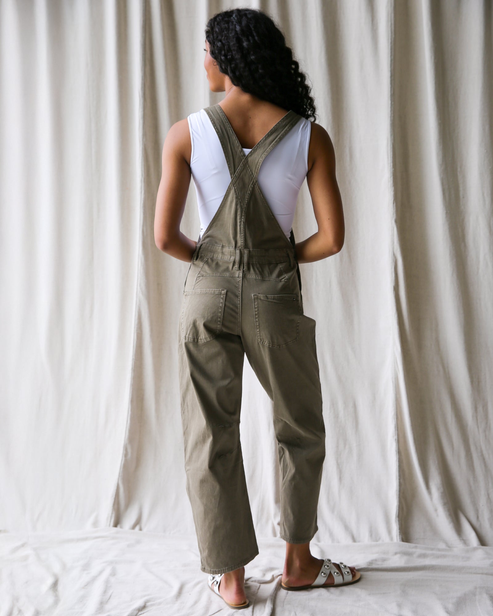 Person wearing green overalls standing against a plain background