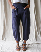 Person wearing navy blue pants with front pockets on a plain background