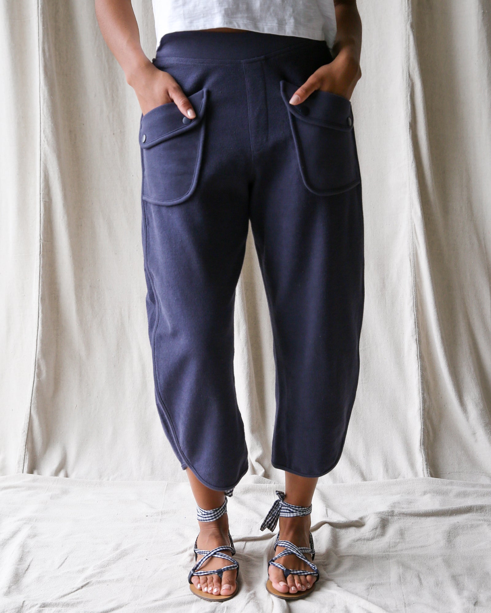 Person wearing navy blue pants with front pockets on a plain background