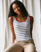 Woman wearing a striped tank top with red trim against a neutral background