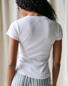 Person wearing a white t-shirt and striped pants against a neutral background