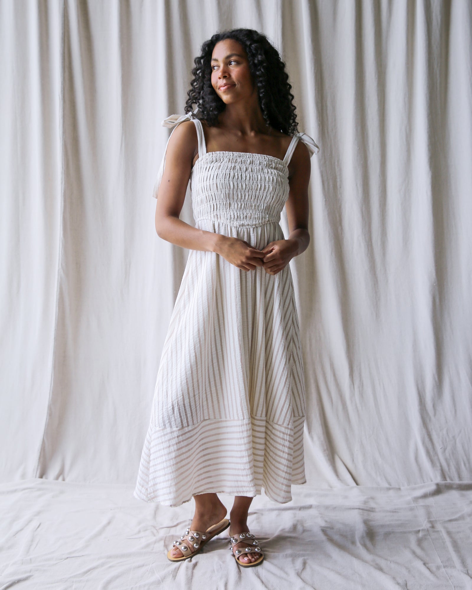 Woman in a white dress against a white curtain background