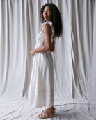 Woman wearing a white dress standing against a plain white background