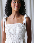 Woman wearing a white dress with bow straps against a neutral background