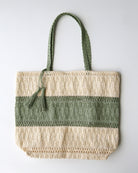 Green and beige woven tote bag with tassel on a white background