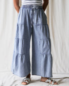 Person wearing light blue tiered pants with a white background