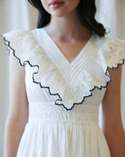 White dress with black lace details on a plain background