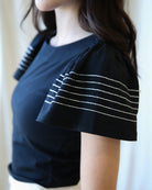 Black top with white striped sleeves worn by a person, blurred background