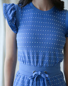 Blue polka dot dress with matching top worn by a person against a neutral background