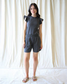 Woman wearing a matching top and shorts set against a white curtain background