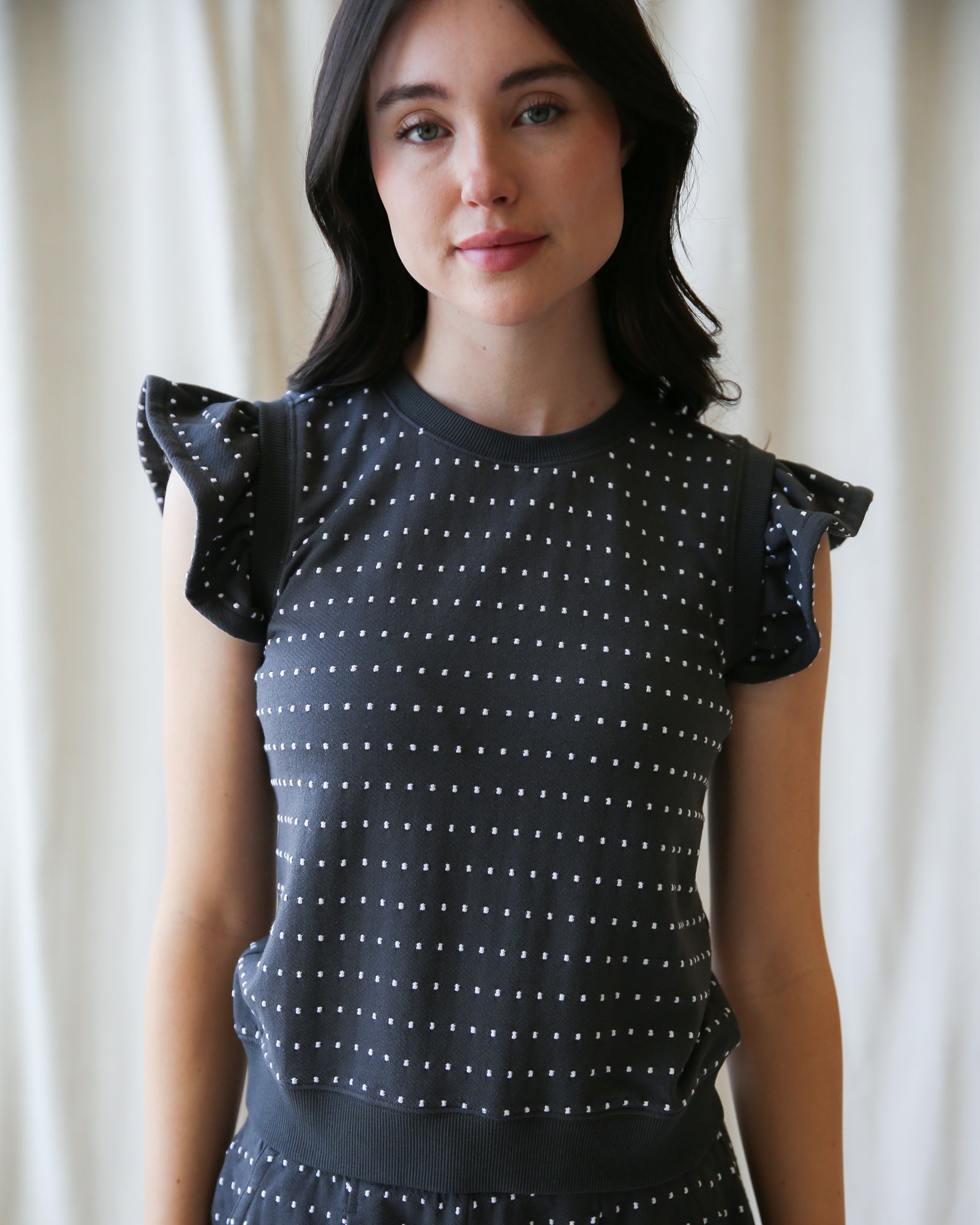 Woman wearing a black dress with white polka dots against a plain background
