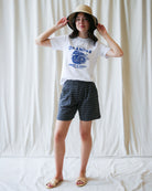 Person wearing a white t-shirt with a graphic design and black shorts against a plain background