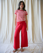 Woman wearing a red and white striped shirt and red pants against a plain background