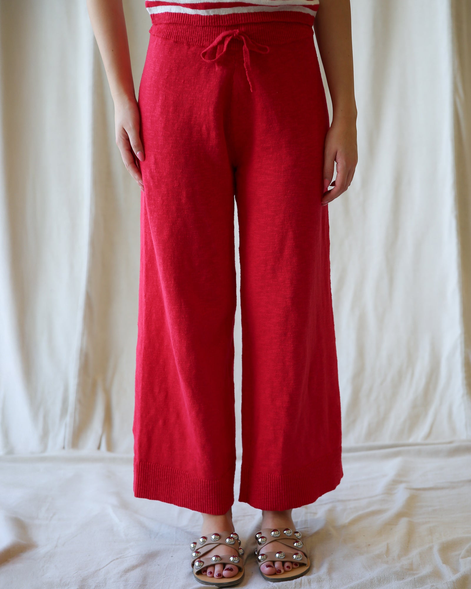Person wearing red wide-leg pants and a striped top against a white background