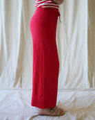 Person wearing red pants and a striped shirt against a white curtain background