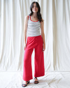 Woman wearing a striped tank top and red pants against a white background