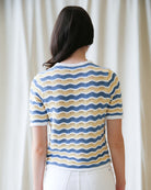 Person wearing a striped shirt with wavy pattern against a plain background