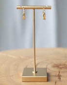 Gold earring stand with gold earrings on a wooden surface