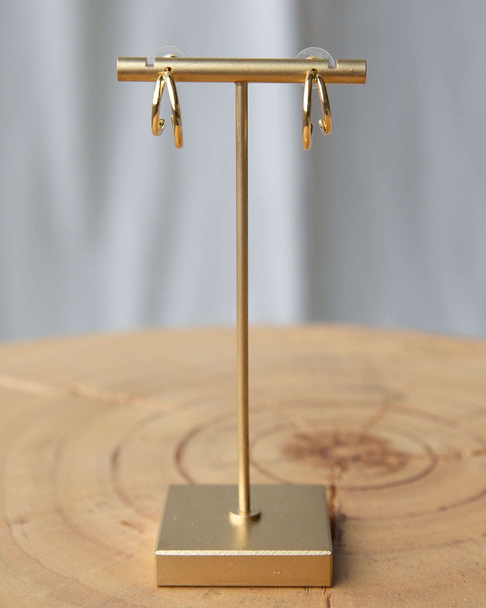 Gold earring stand with gold earrings on a wooden surface