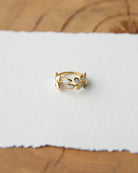 Gold ring with a white stone on a white fabric background
