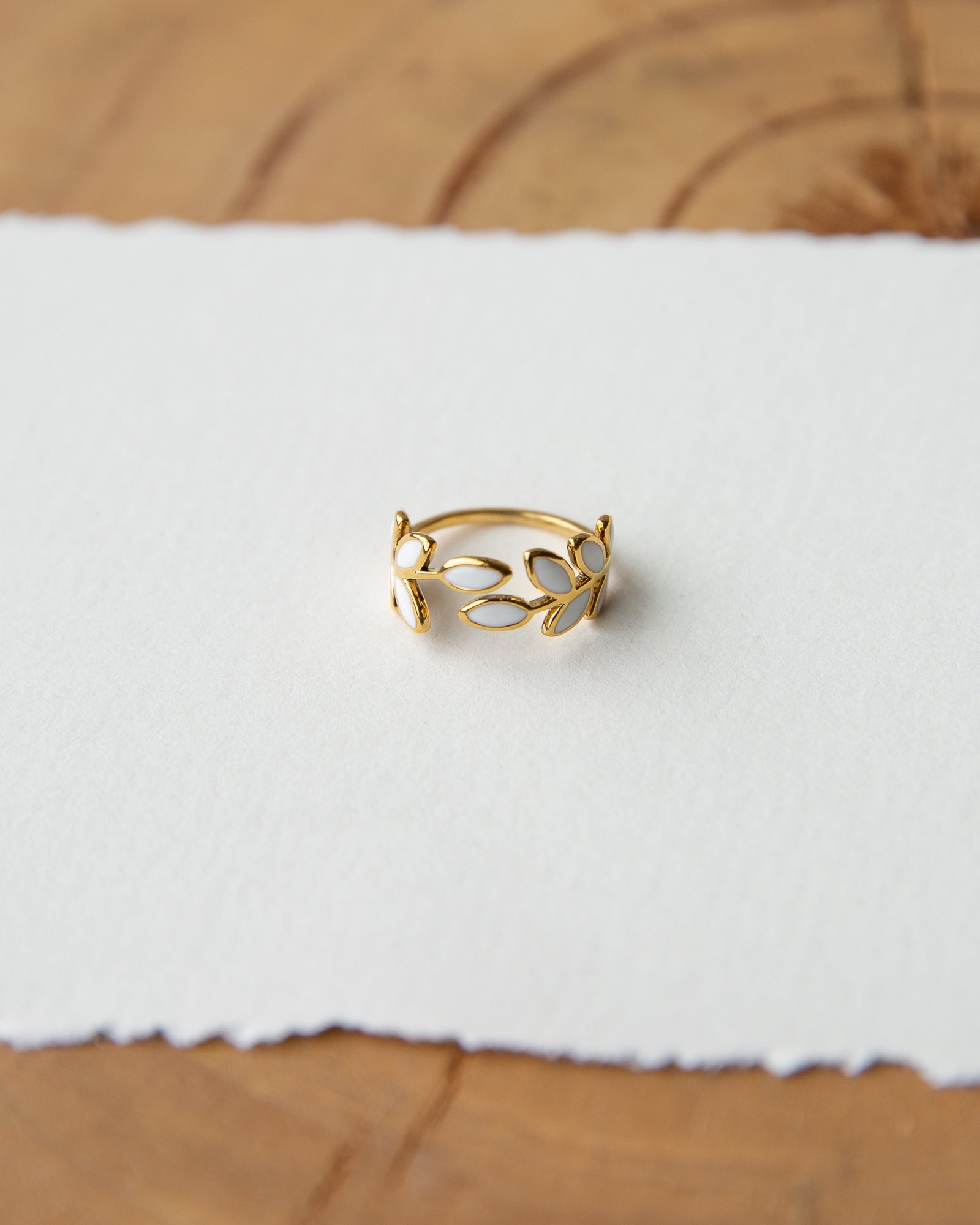 Gold ring with a white stone on a white fabric background