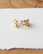 Gold leaf-shaped ring on a white fabric background