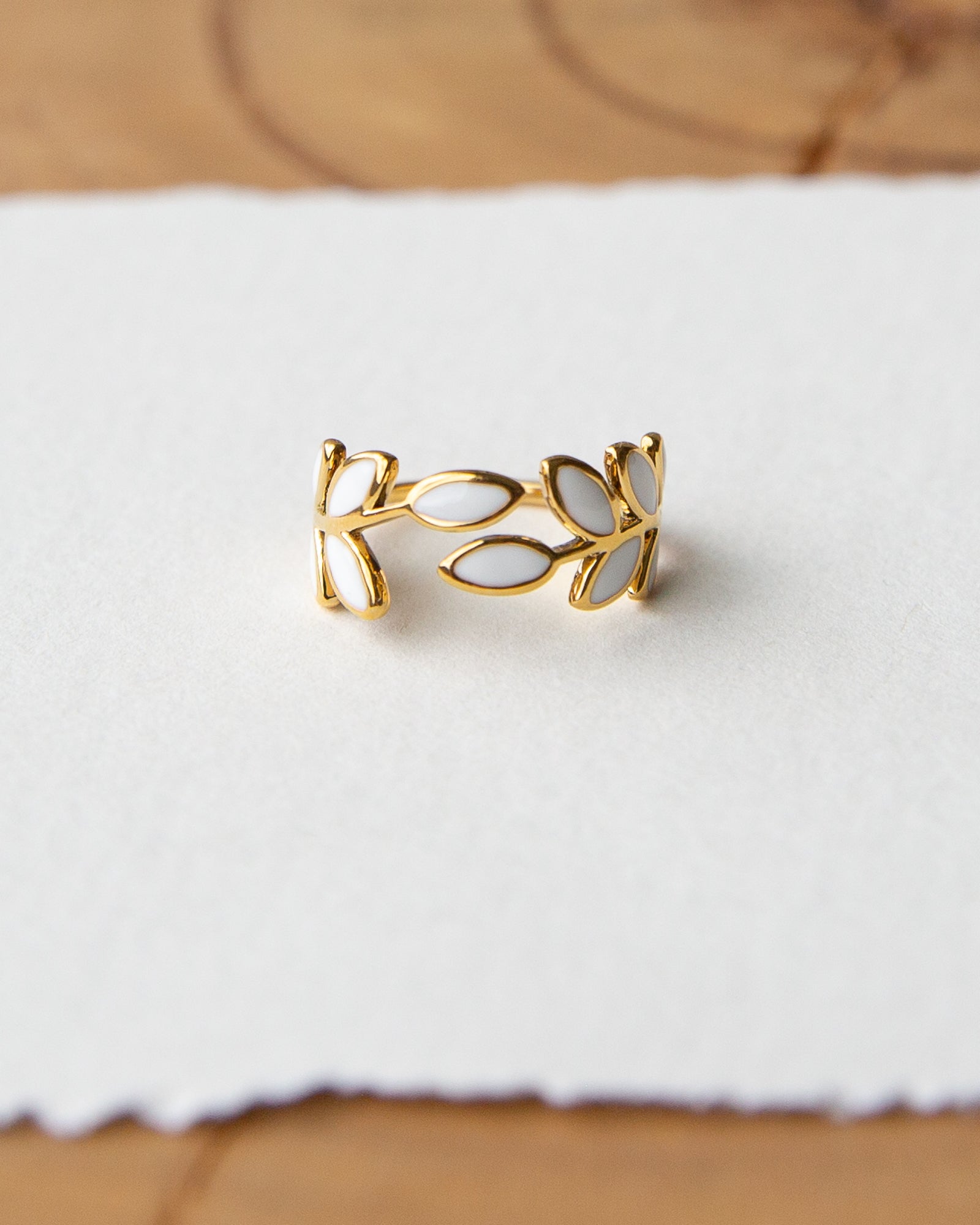 Gold leaf-shaped ring on a white fabric background