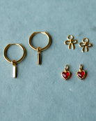 Gold hoop earrings with hanging charms on a light blue background