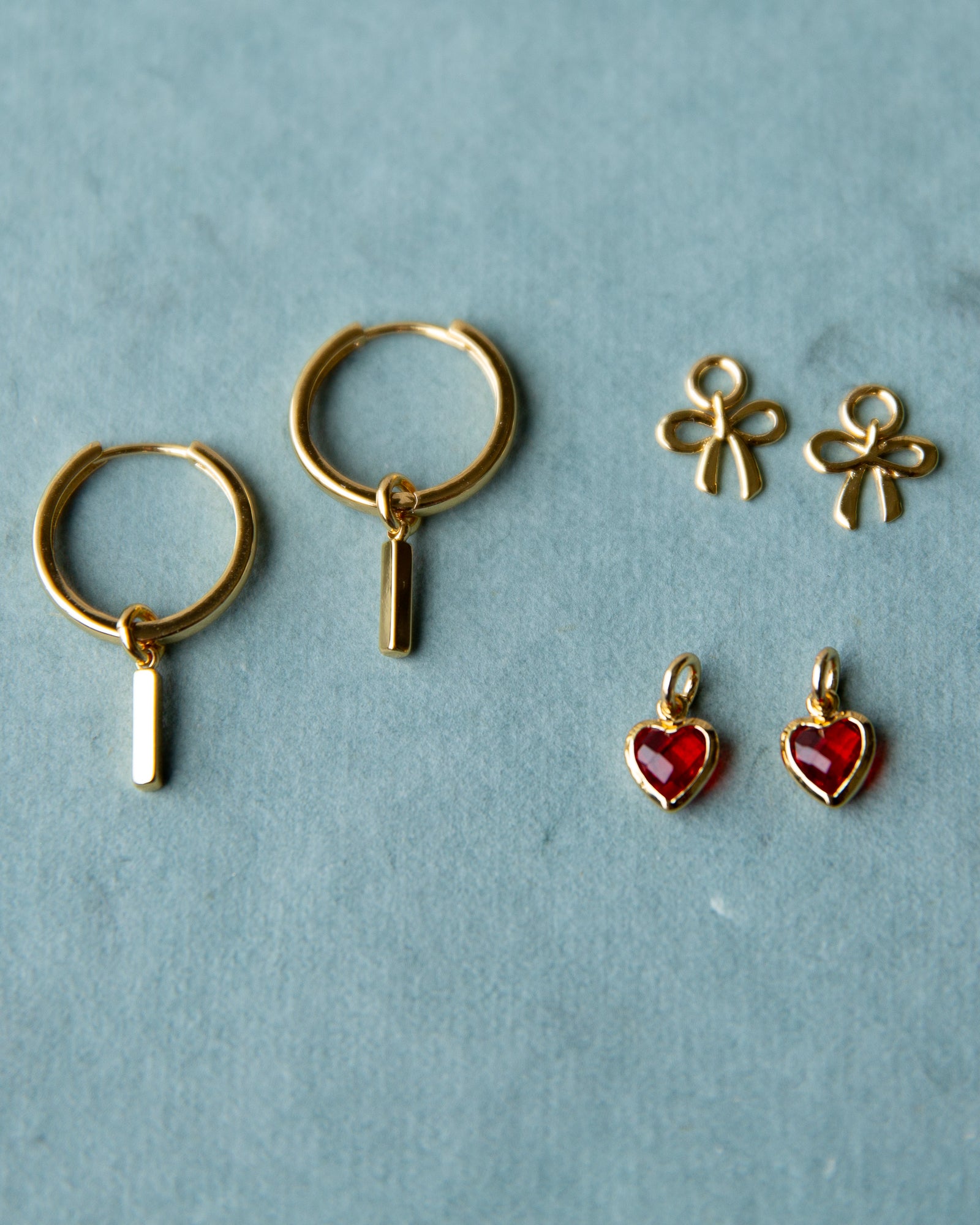 Gold hoop earrings with hanging charms on a light blue background