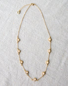 Gold necklace with floral pendants on a light gray background