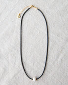 Black necklace with a gold chain on a gray background