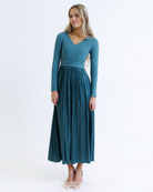 Woman wearing a teal long-sleeve dress on a white background