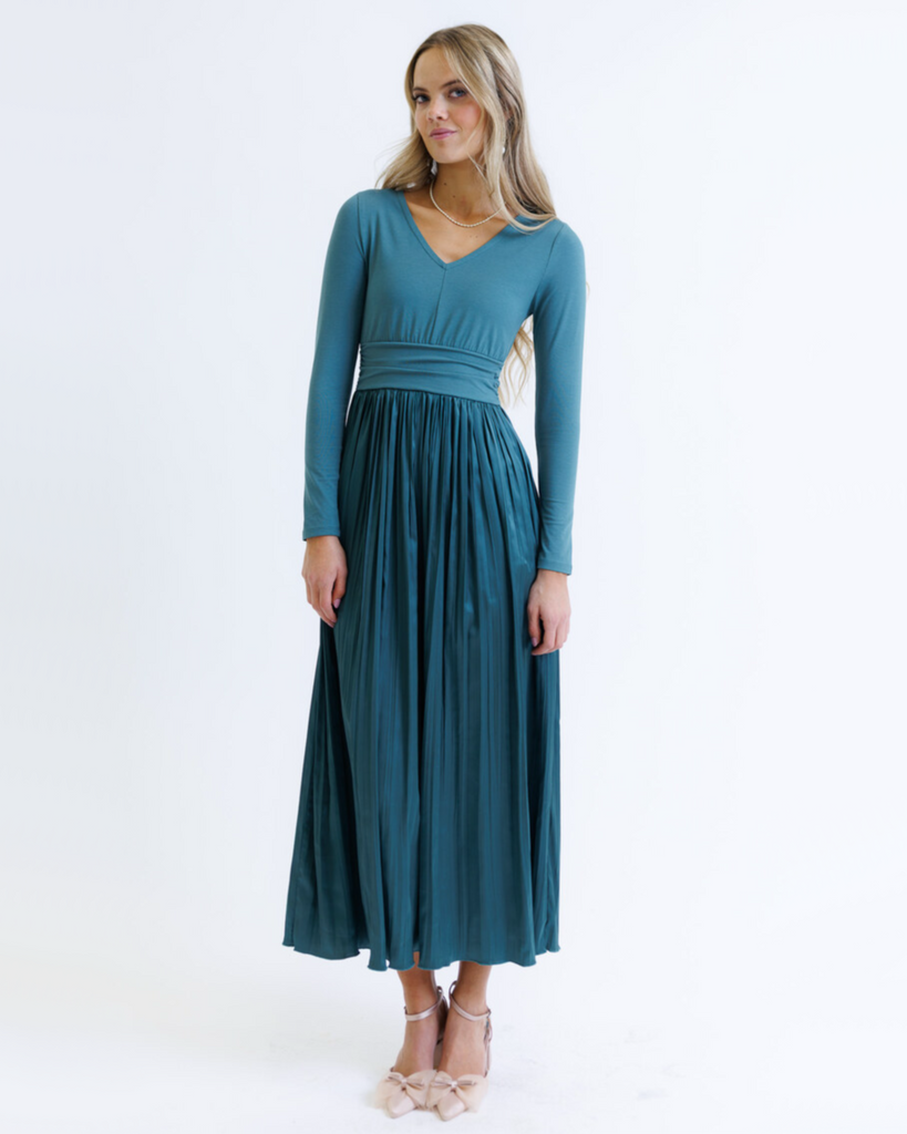 Woman wearing a teal long-sleeve dress on a white background