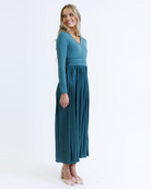 Woman wearing a teal long-sleeve dress on a white background