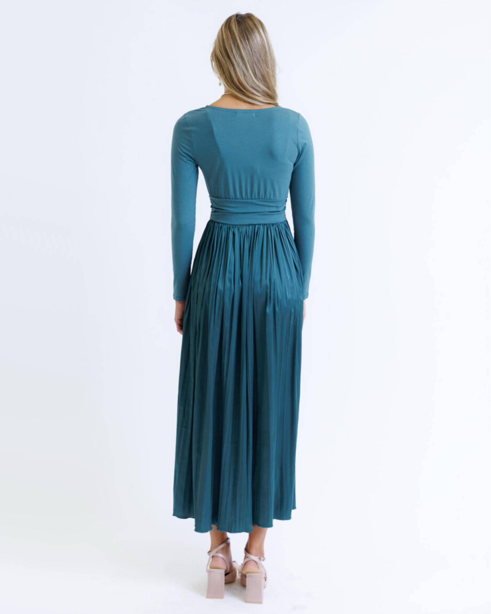 Woman wearing a teal long-sleeve dress on a white background