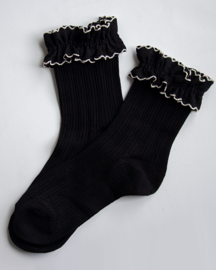 Black socks with ruffled top on a light gray background