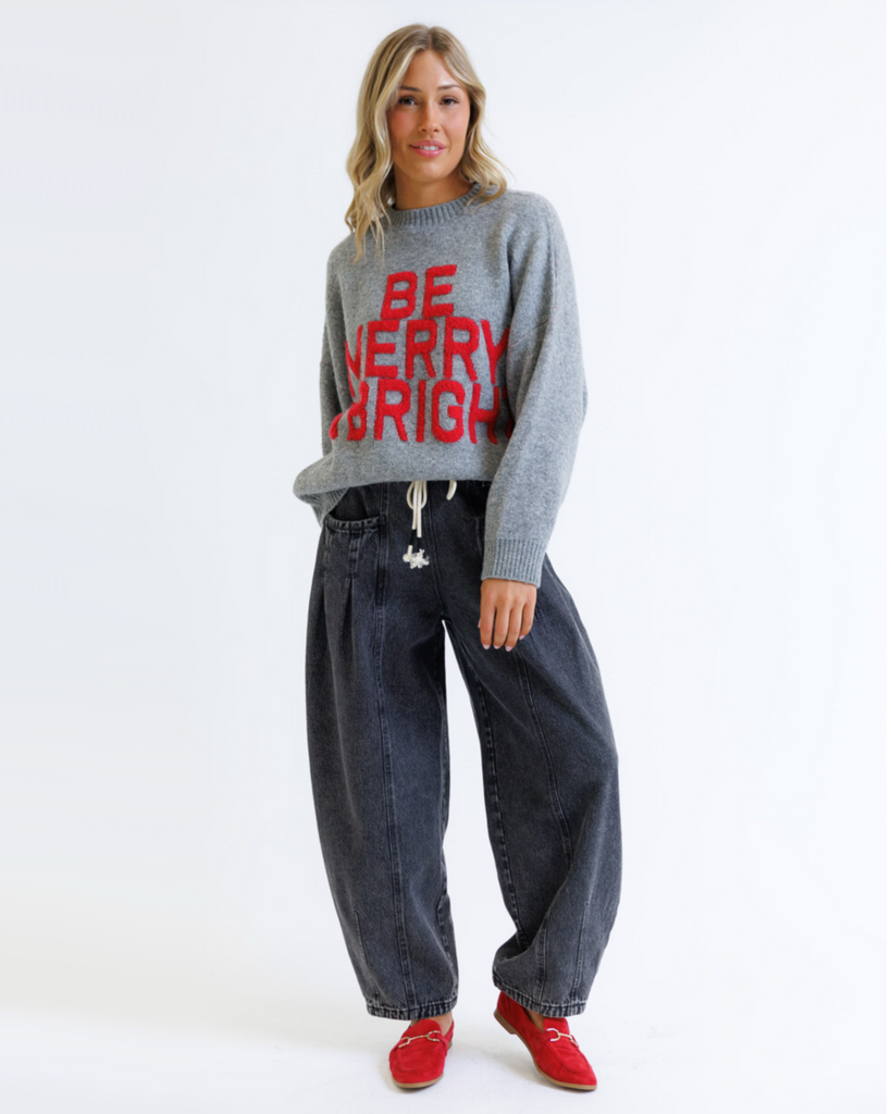 Woman wearing a gray sweater with red text 'BE MERRY & BRIGHT' on a white background