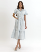 Woman wearing a light blue dress with buttons on a white background