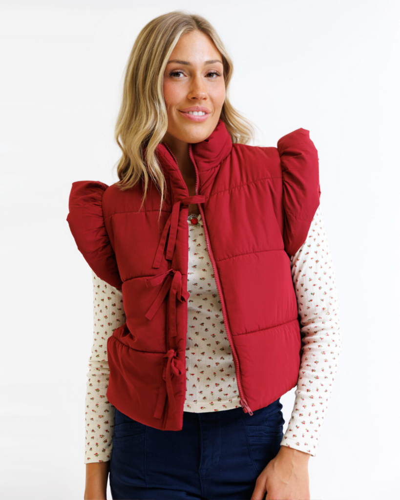 Woman wearing a red vest over a floral shirt on a white background