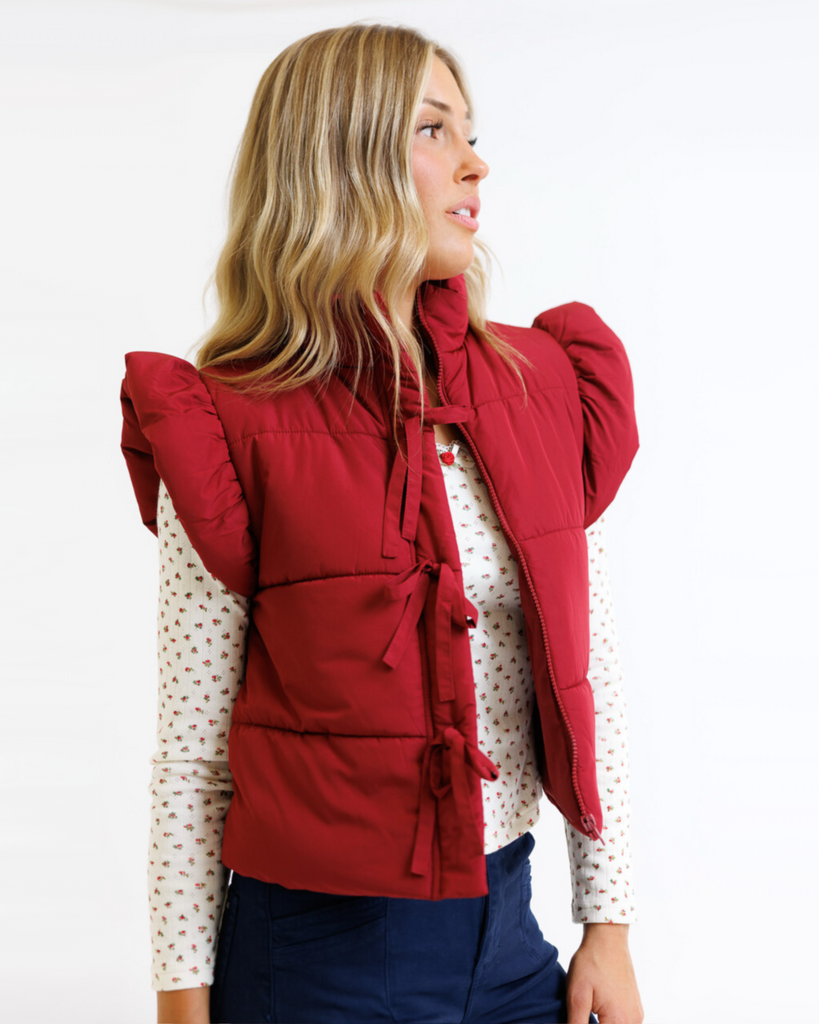 Woman wearing a red vest over a floral shirt on a white background