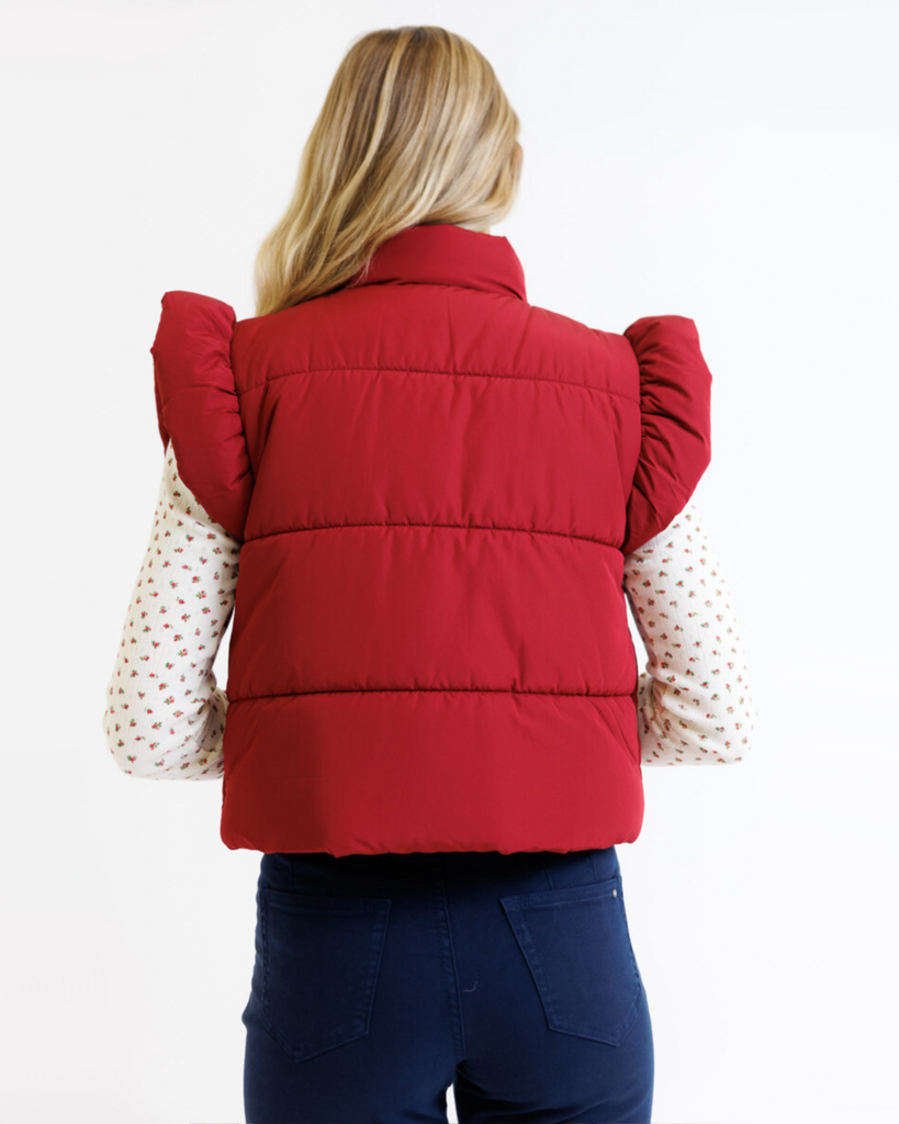 Woman wearing a red vest over a floral shirt on a white background
