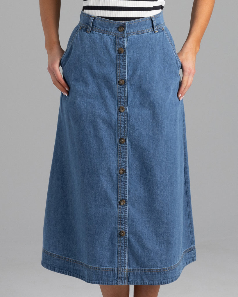 Model wearing a blue denim a-line midi length skirt with buttons down the front.