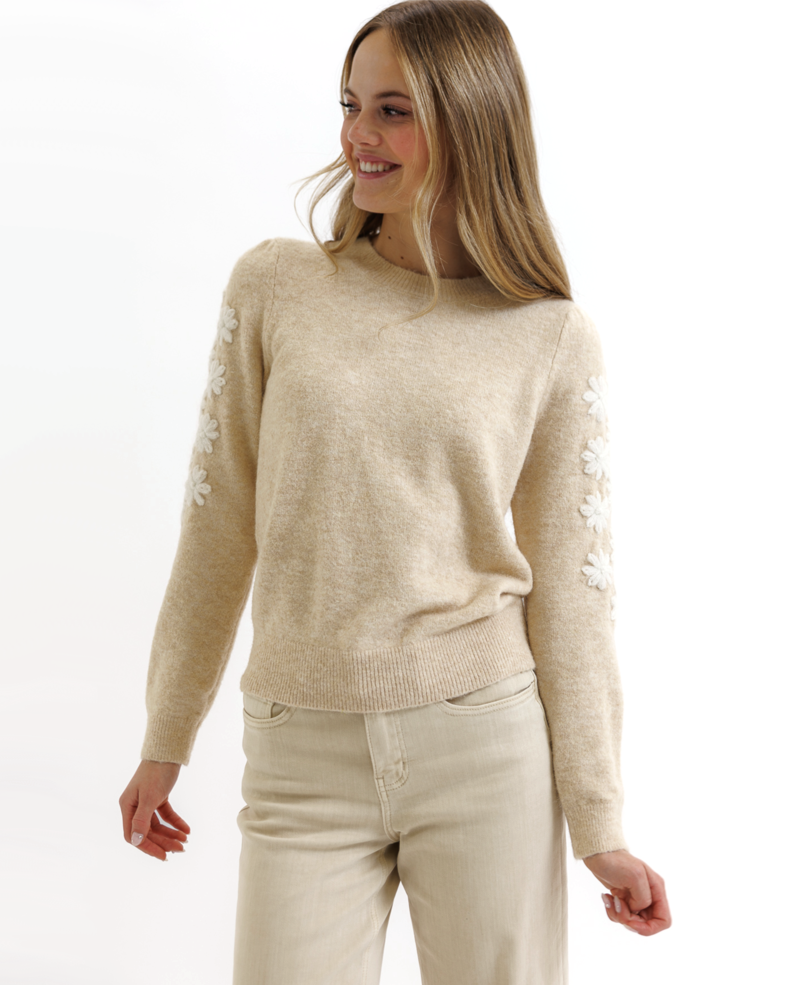 Woman wearing a beige sweater and pants on a white background