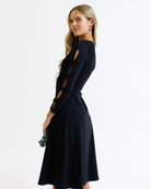Woman wearing a black dress with cut-out sleeves on a white background