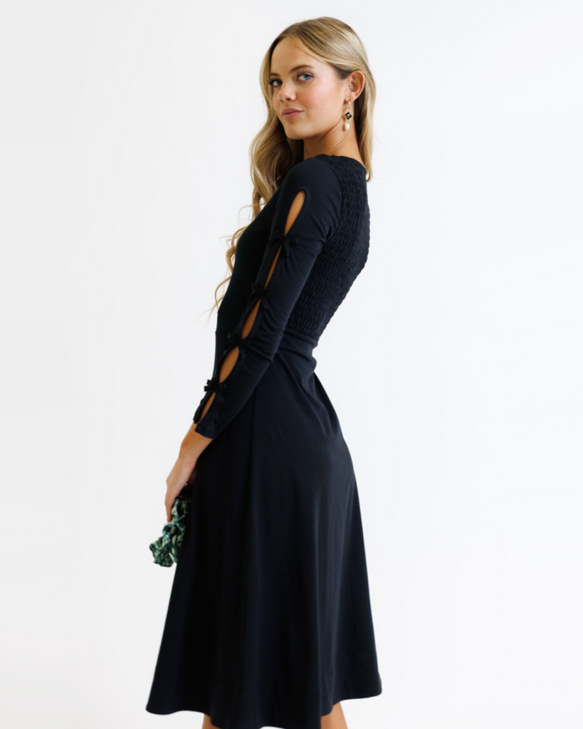 Woman wearing a black dress with cut-out sleeves on a white background