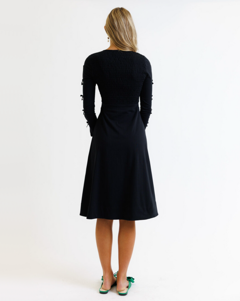 Woman wearing a black dress with long sleeves on a white background